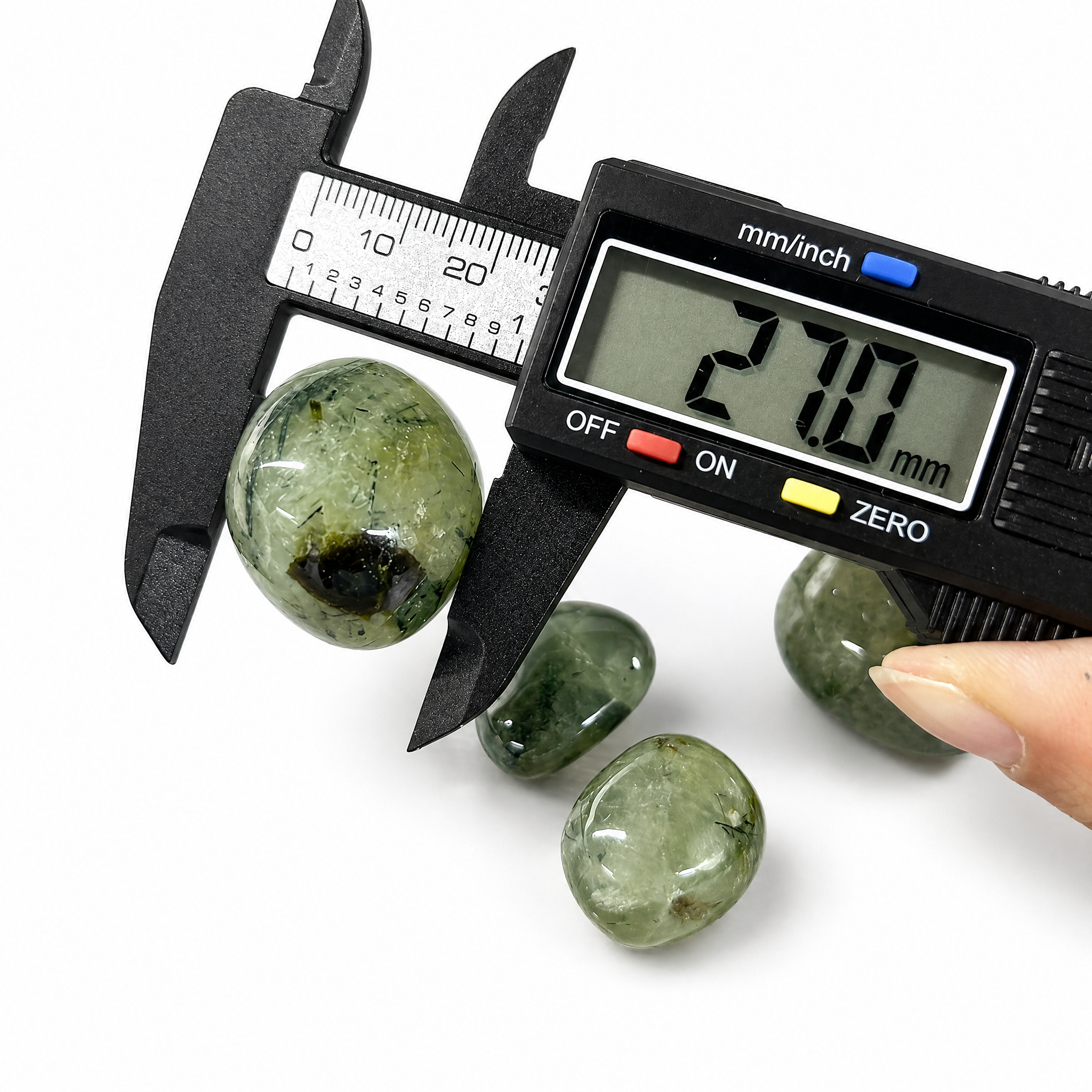 VoraZen™ Natural Prehnite Tumbled Stones in a white porcelain bowl. These translucent pale green crystals, sized approx 23-28mm, feature unique dark Epidote inclusions. Known as the "Stone of Healing," they offer a high-quality polished finish for meditation and heart chakra work.